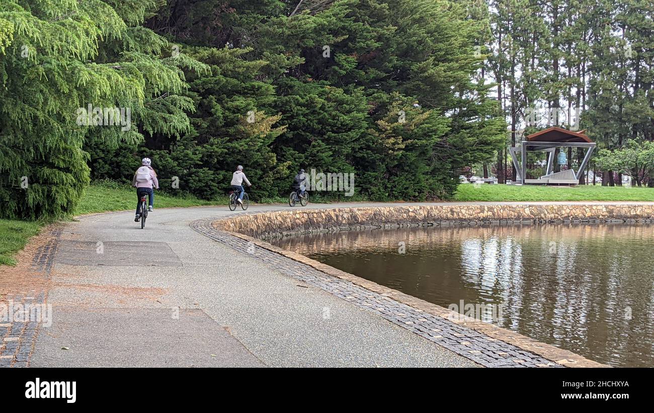 Biker radeln am Teich entlang in einem Park Stockfoto