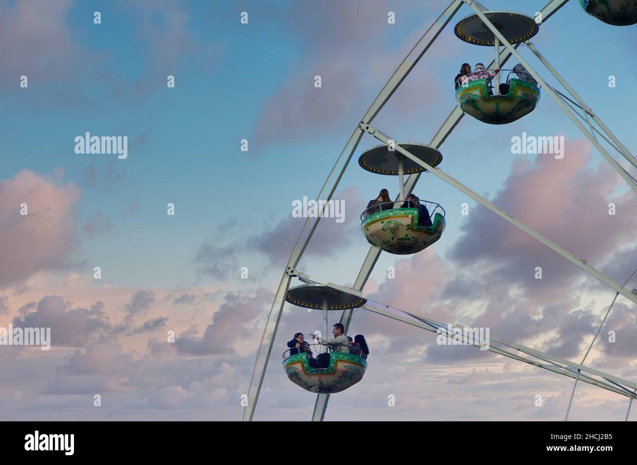 Familien genießen Fahrten in geschlossenen Gondeln bei einer großen Riesenradbeobachtungsfahrt im Berliner Vergnügungspark vor dramatischem Abendhimmel. Riesenrad Stockfoto