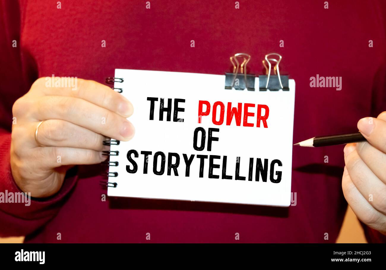 Der Mann hängt einen roten Aufkleber mit dem Text The Power of Storytelling Overlay auf seinem weißen Hemd Stockfoto