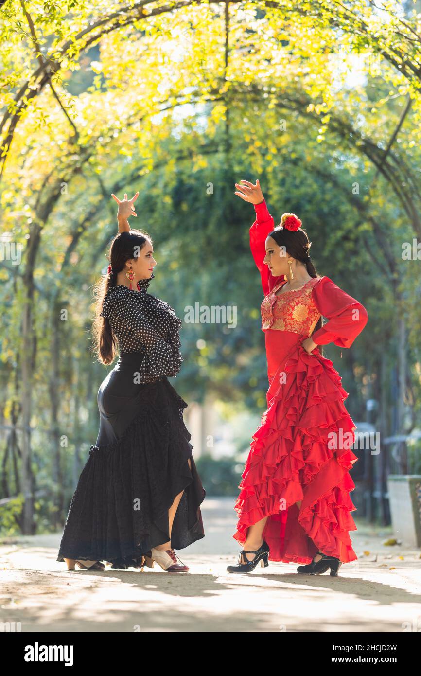 Zwei Frauen in Flamenco-Kostümen, die von einem Pflanzenbogen umgeben tanzen Stockfoto