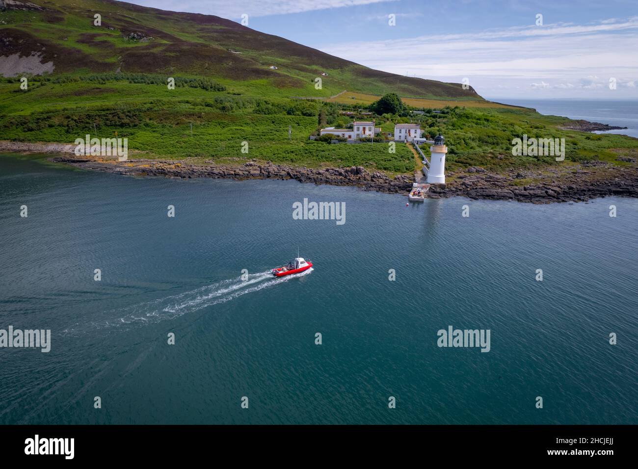 Kleine rote Fähre, die an einem entlegem Leuchtturm ankommt Stockfoto