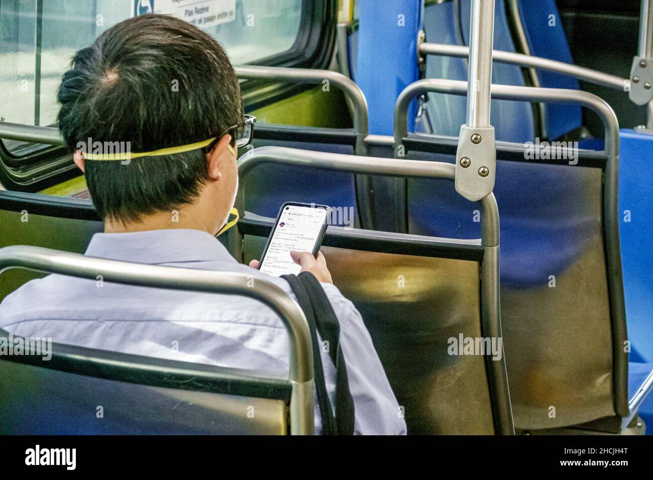 Miami Florida Miami-Dade Metrobus an Bord Passagier Fahrer trägt Gesichtsmaske Mann im Innenbus öffentlichen Verkehrsmitteln mit Lesung Texting messag Stockfoto