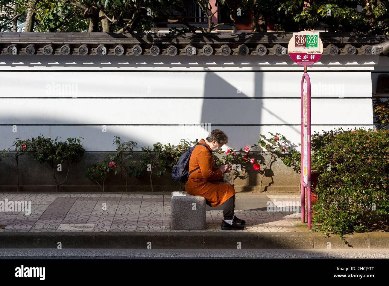Eine ältere Japanerin sitzt an einer Bushaltestelle in Kappabashi, in der Nähe von Ueno Tokyo, Japan. Stockfoto