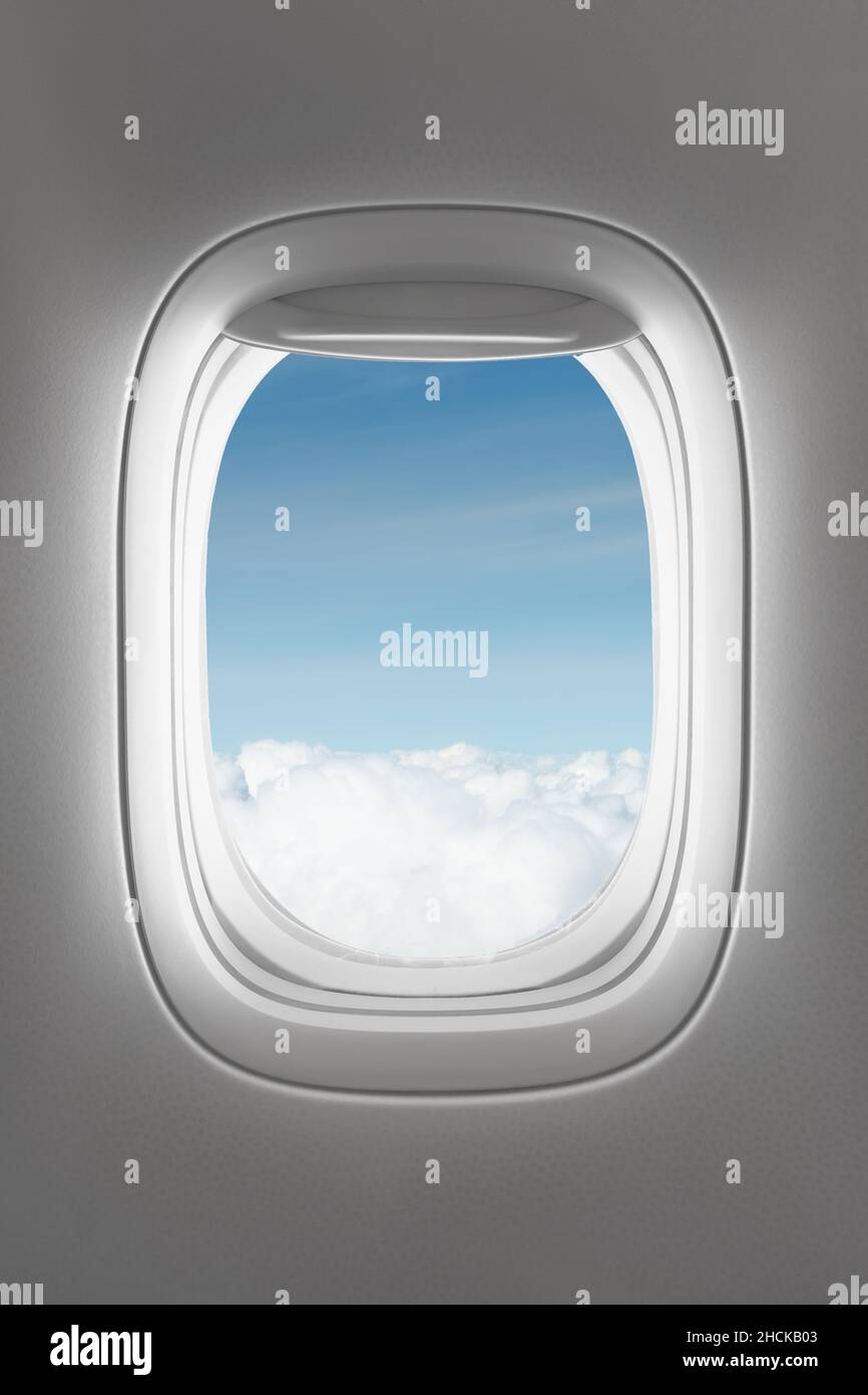 Blick durch ein großes Passagierflugzeugfenster, über den Wolken Stockfoto
