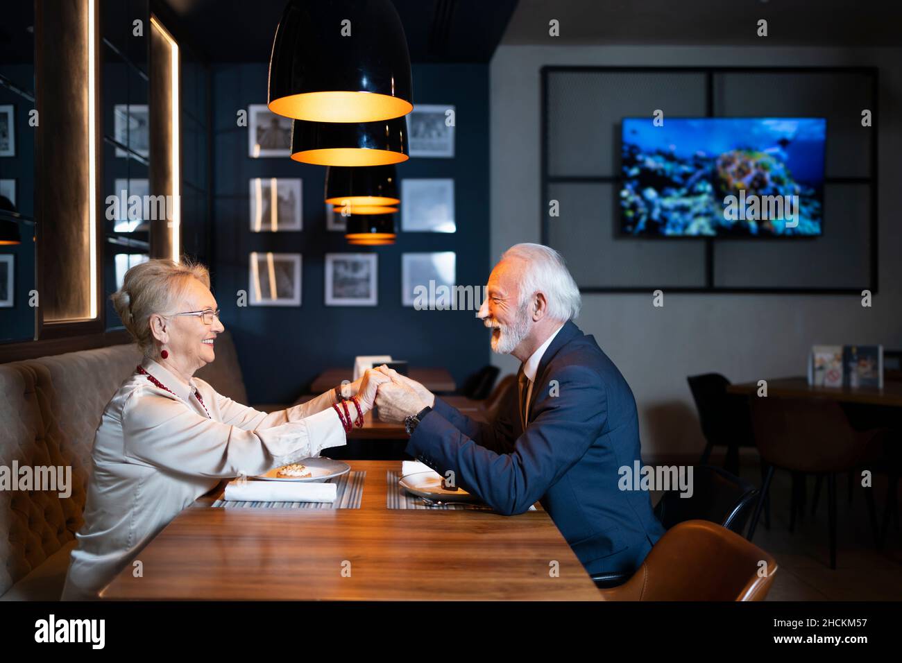 Ältere Paare, die sich in einem modernen Restaurant gegenseitig ihre Liebe zum Ausdruck bringen Stockfoto