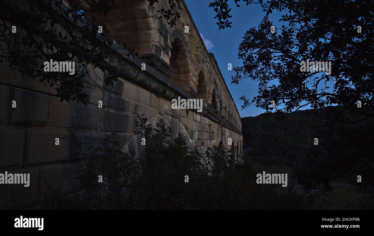 Schöner Blick auf das antike römische Aquädukt Pont du Gard, das im Dunkeln aus großen Steinblöcken in der Nähe von Vers-Pont-du-Gard, Oczitanie, Frankreich, erbaut wurde. Stockfoto