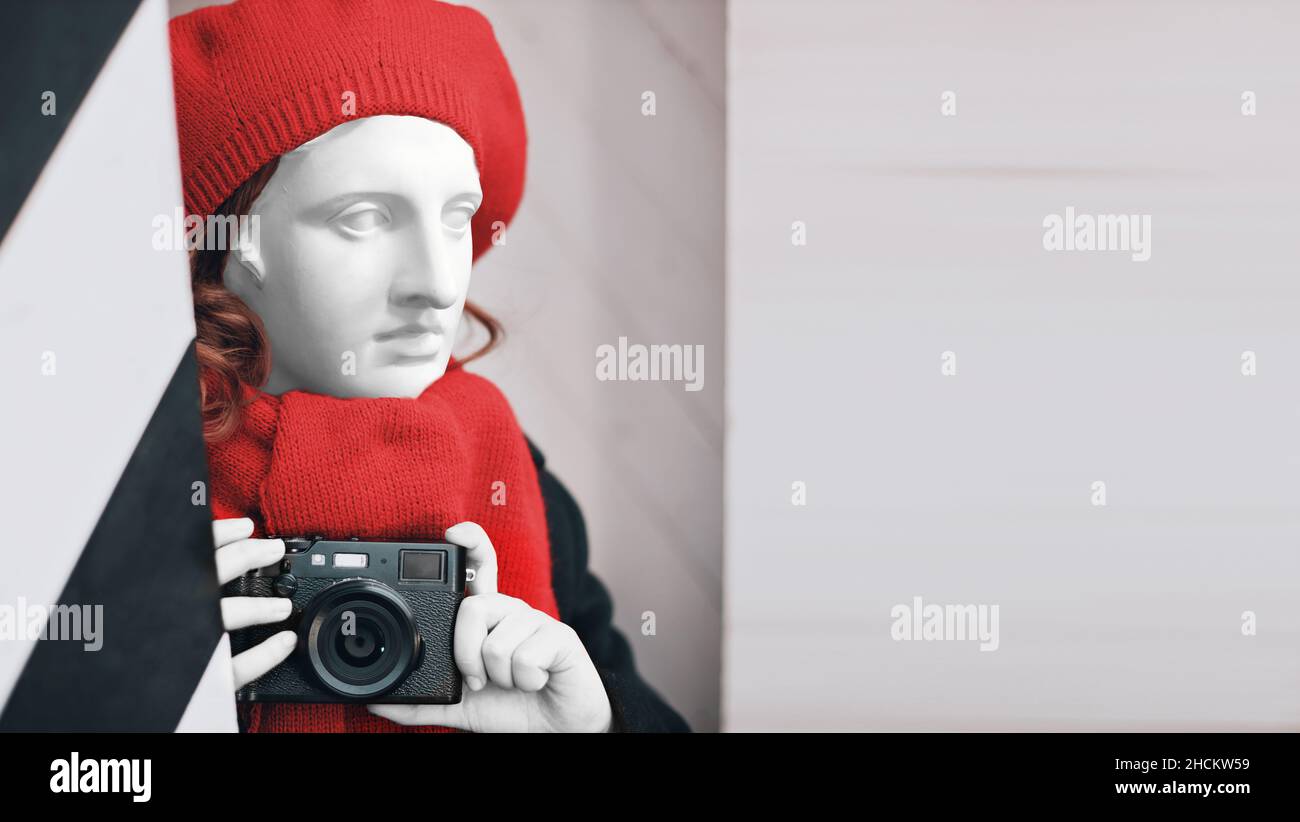 Gips-Statue in einer roten Baskenmütze und Schal mit einer Kamera in den Händen. Fotografie Kunst Symbol. Hochwertige Fotos Stockfoto