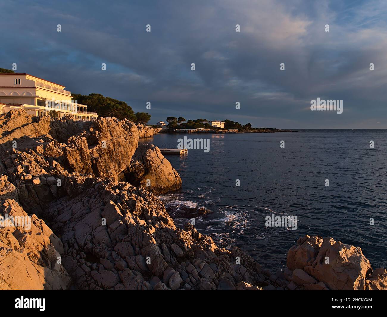 Schöner Blick auf die felsige mittelmeerküste von Antibes, Französische Riviera, Frankreich an der Bucht der Milliardäre in der Abendsonne mit ruhigem Meer. Stockfoto