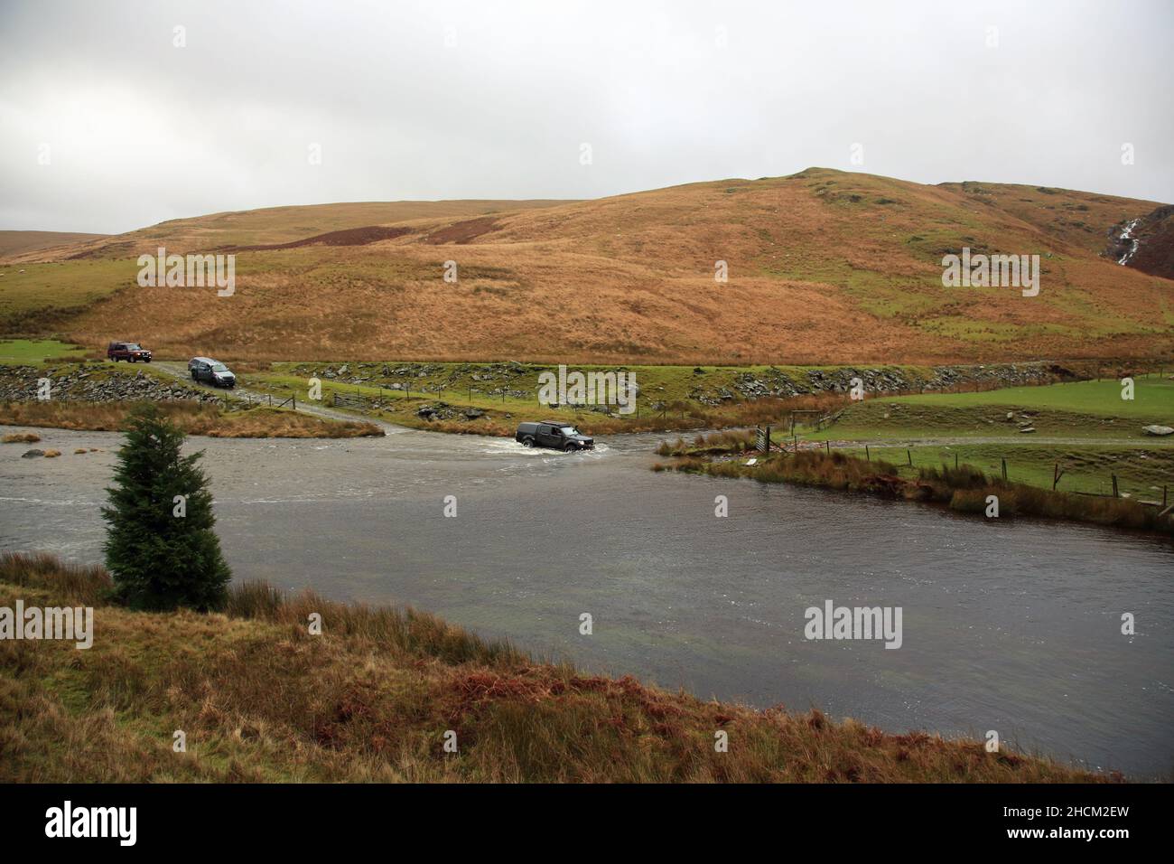 Geländewagen, der im Elan Valley, Powys, Wales, Großbritannien, durch Wasser fährt. Stockfoto