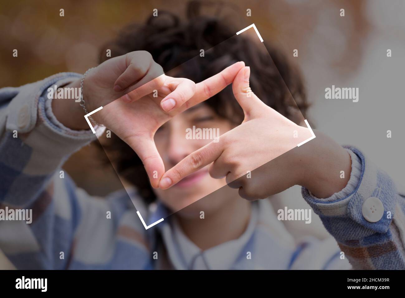 Junge Brünette Frau mit lockigen Haaren, die das Zeichen „Framing“ mit ihren Händen macht Stockfoto