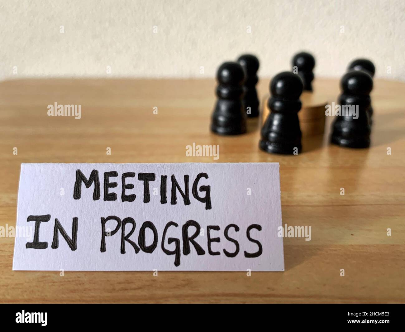 Geschäftsmeetingkonzept mit Schachfigur, die einen Tisch umkreist, und einer Notiz des laufenden Treffens. Stockfoto