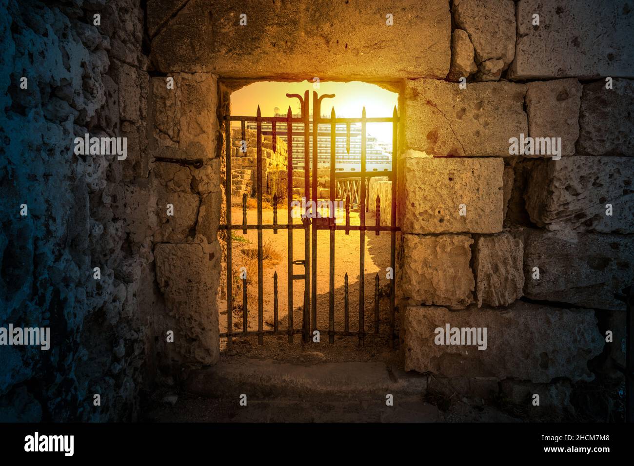 Sonnenlicht scheint durch ein geschlossenes, geheimnisvolles altes Tor. Stockfoto