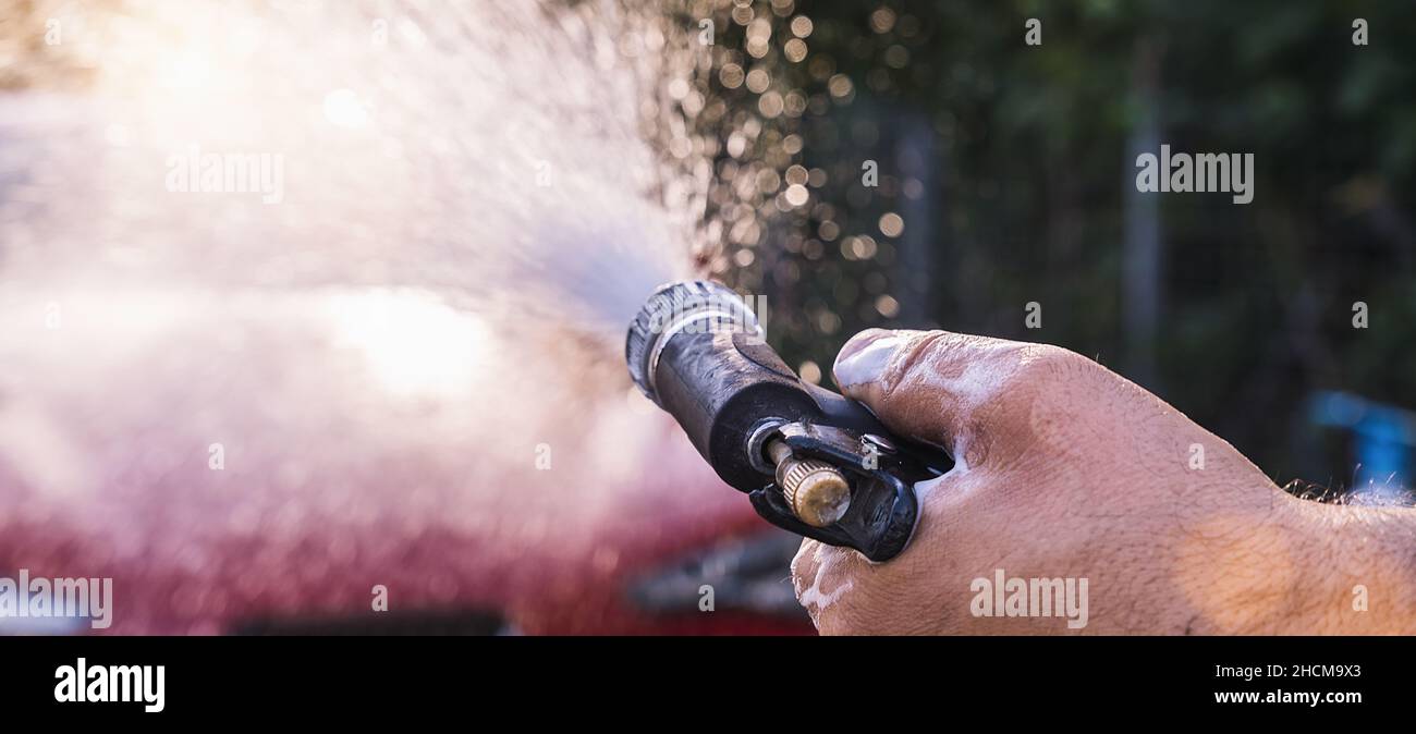 Sprühen von Schaum auf einen roten Sportwagen mit Hochdruckschaum Pistole Autowäsche bei Autowäsche Stockfoto