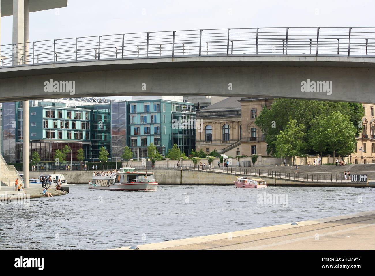 Blick auf die Spree im Sommer auf das Paul-Loebe-Gebäude mit Bootstouren und vielen Menschen. Gebäude und klarer blauer Himmel Hintergrund. Stockfoto