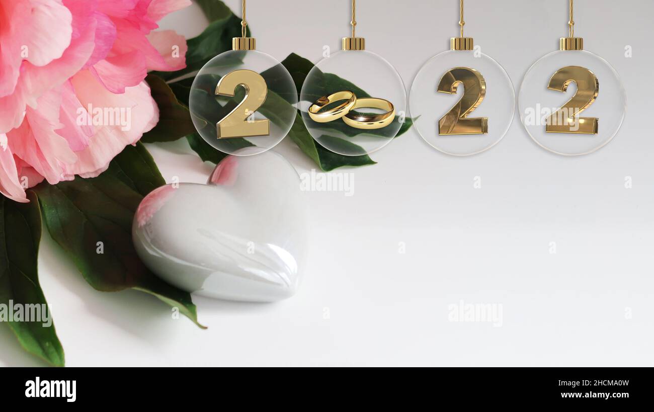 goldene Eheringe Glaskugel 2022-stellig schöne rosa Blume auf grünem Blatt und weiß glänzendes Herz - Kopierraum Stockfoto