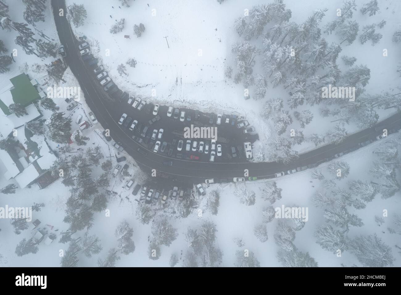 Drohnenantenne eines Parkplatzes auf dem verschneiten Waldberg im Winter. Wintersaison Stockfoto