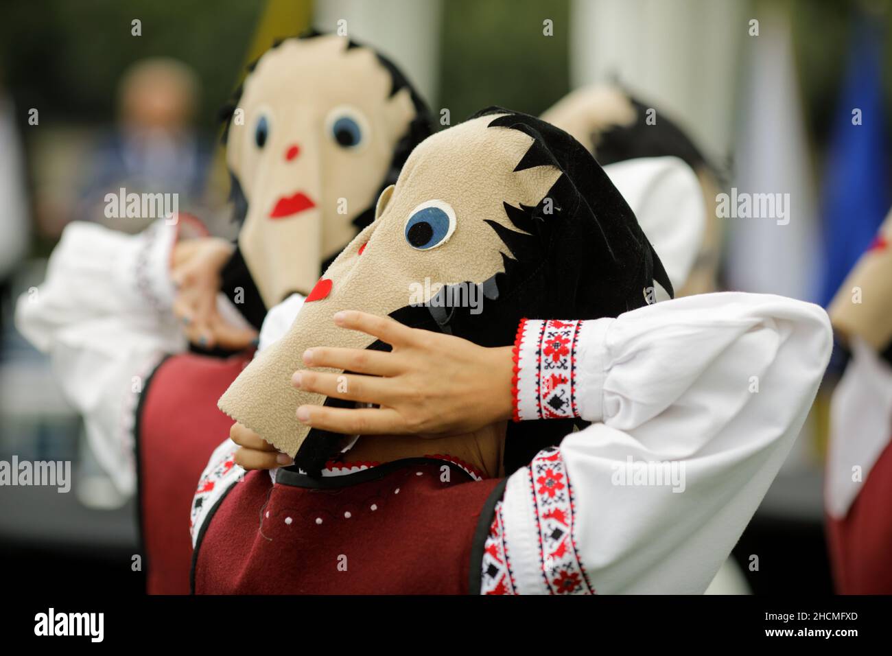 Braila, Rumänien - 26. August 2021: Frauen, die in traditionellen rumänischen Kostümen und mit rituellen Doppelgesichtsmasken gekleidet sind, führen einen traditionellen Tanz auf. Stockfoto