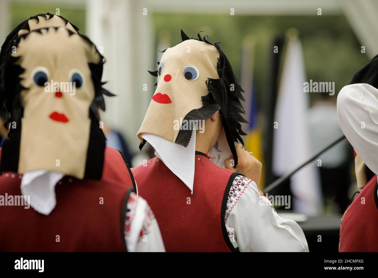 Braila, Rumänien - 26. August 2021: Frauen, die in traditionellen rumänischen Kostümen und mit rituellen Doppelgesichtsmasken gekleidet sind, führen einen traditionellen Tanz auf. Stockfoto