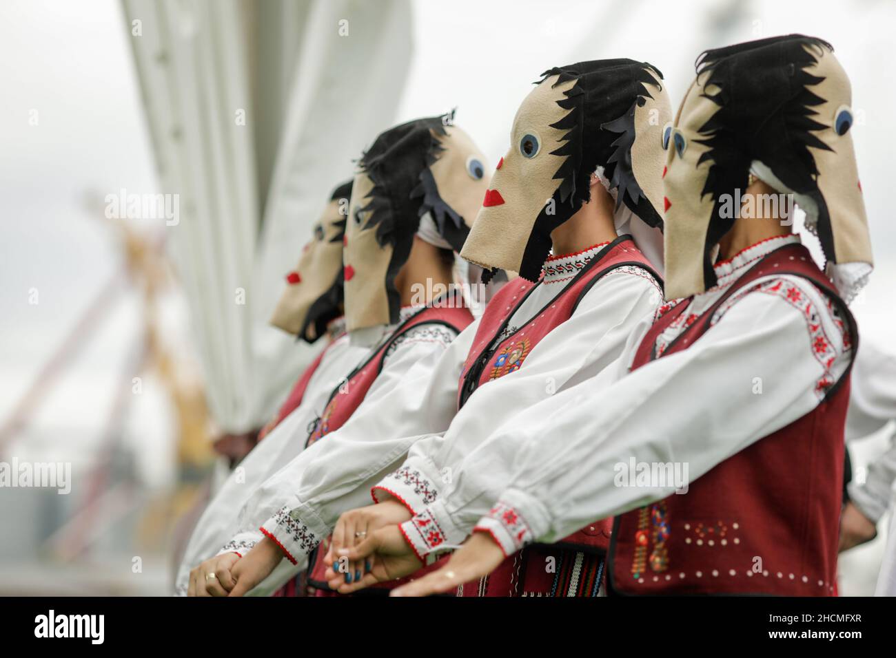 Braila, Rumänien - 26. August 2021: Frauen, die in traditionellen rumänischen Kostümen und mit rituellen Doppelgesichtsmasken gekleidet sind, führen einen traditionellen Tanz auf. Stockfoto