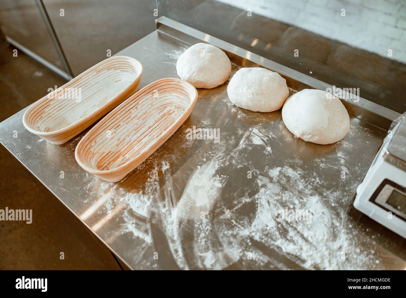 Geschirr, roher Teig und vereinzelte Mehl auf Metalltisch in der Bäckerei-Werkstatt Stockfoto