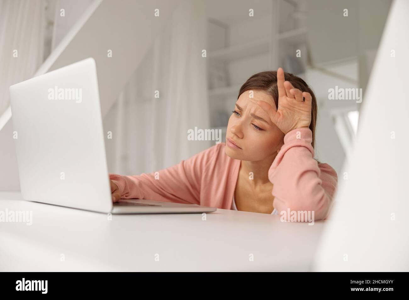 Müde junge Dame, die zu Hause am Laptop arbeitet Stockfoto