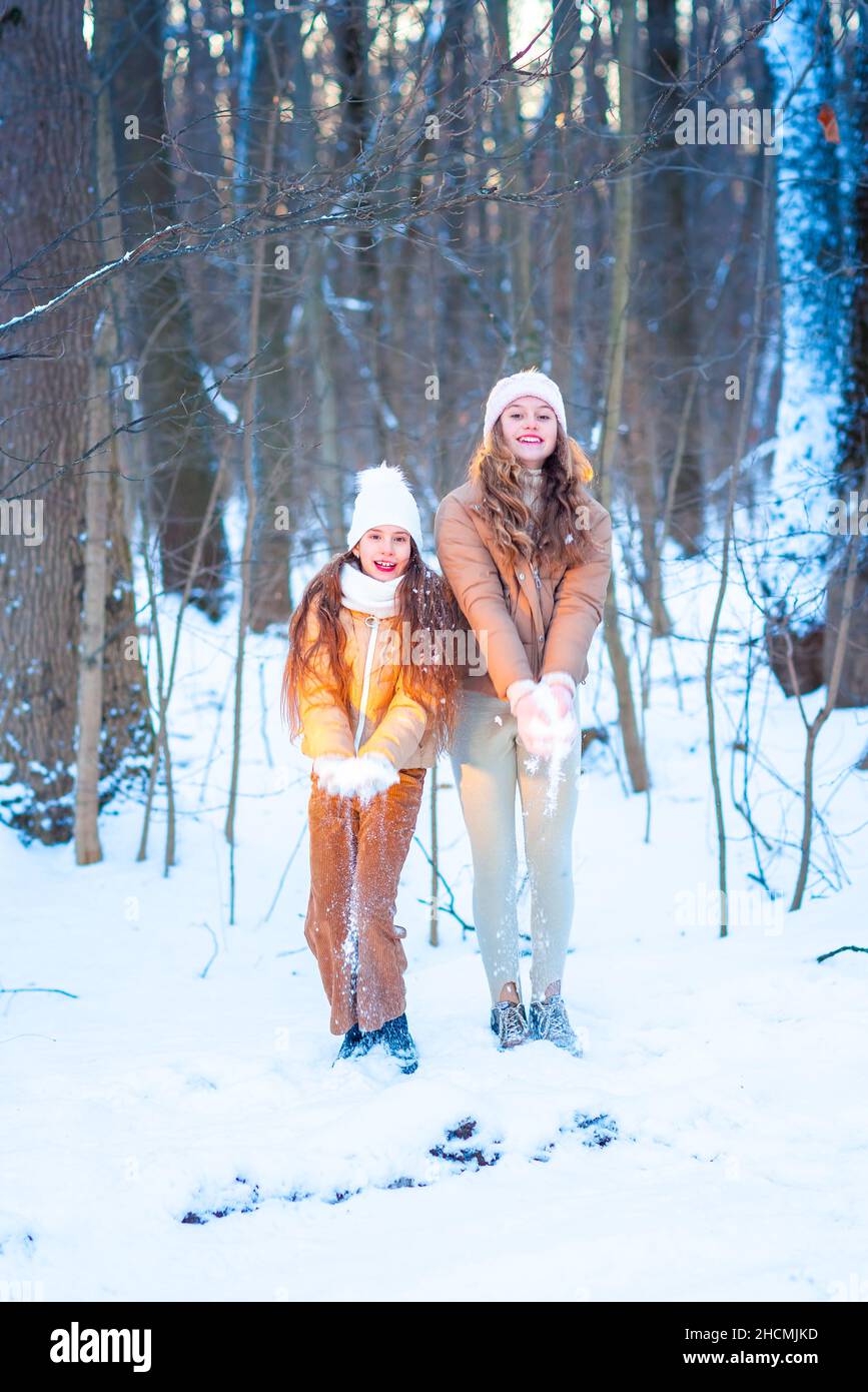 Zwei Mädchen im Teenageralter, die an einem verschneiten Wintertag im Wald mit Schnee spielen. Schnee-Spiele. Winterurlaub. Stockfoto