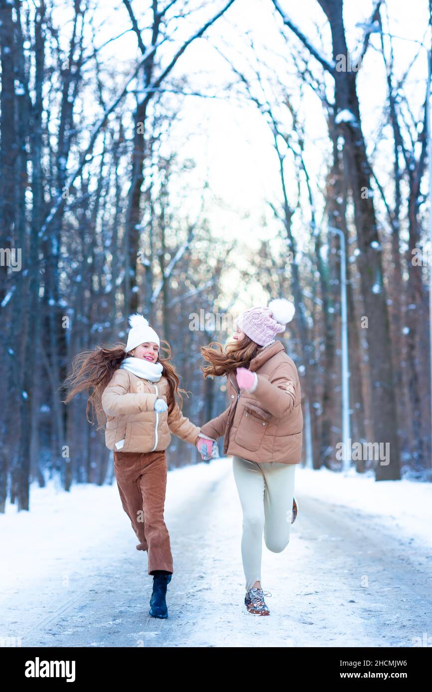 Zwei Mädchen im Teenageralter, die an einem verschneiten Wintertag im Wald mit Schnee spielen. Schnee-Spiele. Winterurlaub. Stockfoto