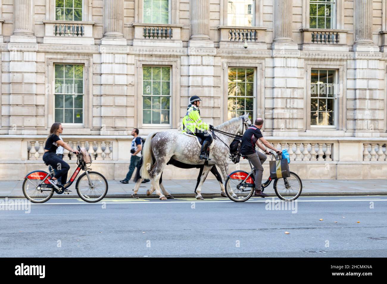 Polizisten auf Pferden und Radfahrern mieten Santander-Fahrräder, die in Whitehall, London, Großbritannien, fahren Stockfoto