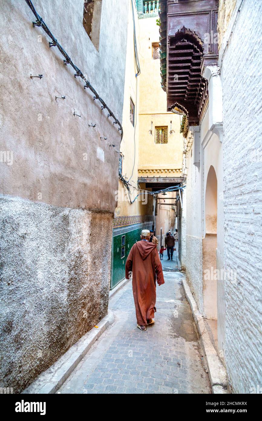 Mann mit einem traditionellen Djellaba Kaftan und Hut, der in der engen Straße in der Medina, Fez, Marokko, herumläuft Stockfoto