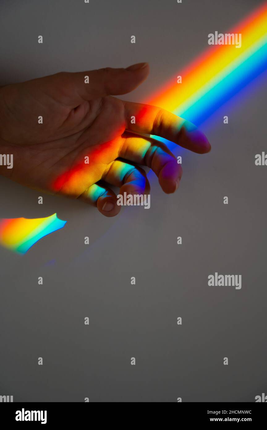 Regenbogenstrahl auf der Hand einer Frau. Stockfoto