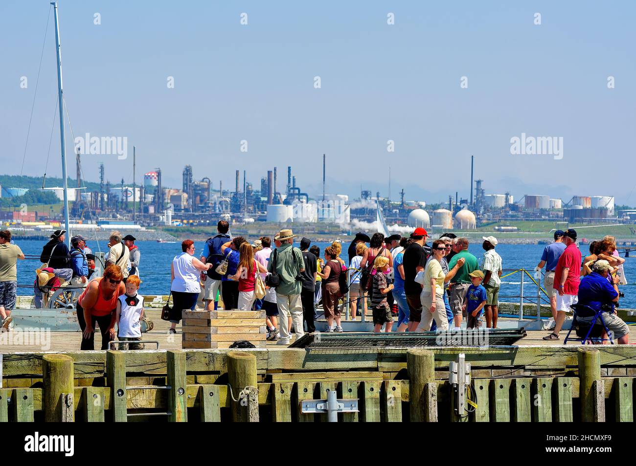 Halifax, Kanada - 19. Juli 2009: Eine Menschenmenge trifft sich an der Halifax Waterfront, einem beliebten Touristenziel. In ist eine Ölraffinerie in Dartmouth zu sehen Stockfoto