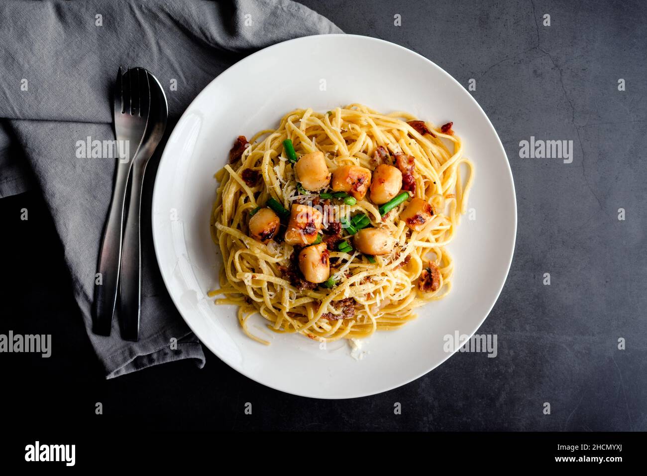 Pasta Carbonara mit Linguine und garniert mit in der Pfanne gebratenen Jakobsmuscheln: Nudeln in einer cremigen Sauce mit Parmigiano Reggiano und Eigelb garniert w Stockfoto