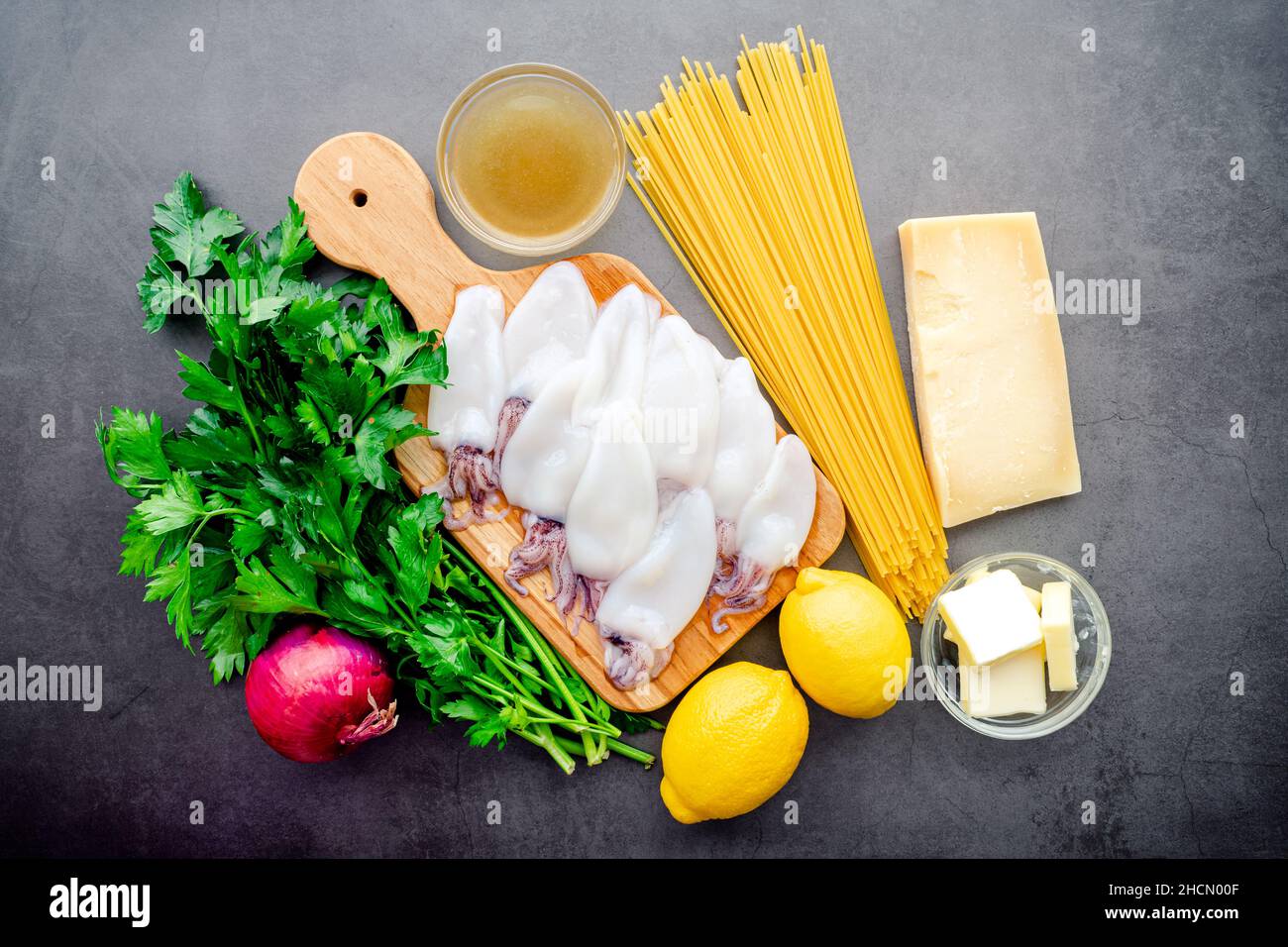 Overhead View of Squid Piccata Zutaten: Rohe Tintenfischröhrchen und Tentakeln, Linguine-Nudeln und andere Piccata-Zutaten Stockfoto