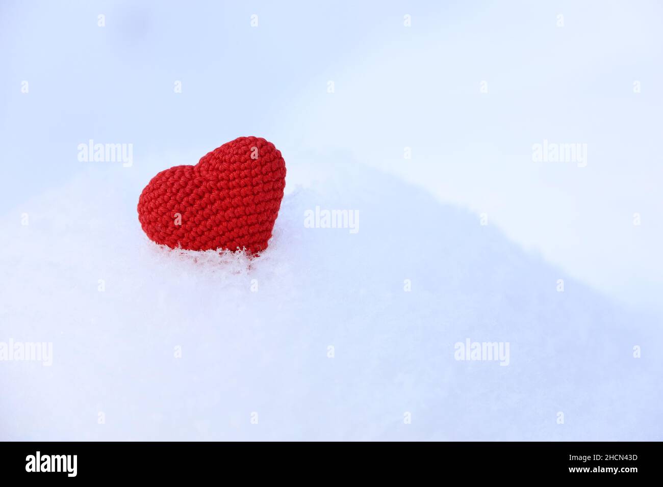 Rot gestricktes Liebesherz im Schnee. Valentinskarte, Hintergrund für Weihnachten oder Neujahr Stockfoto