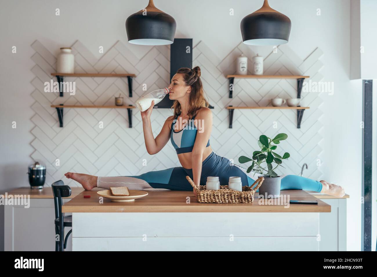 Fit Frau in geteilter Position auf dem Küchentisch beim Frühstück Stockfoto