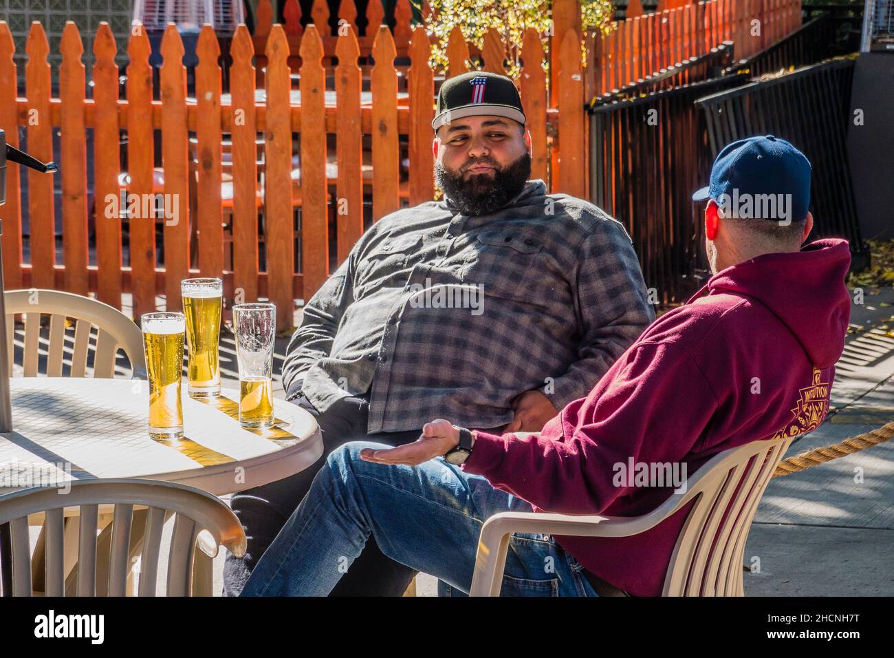 Zwei männliche Biertrinker sitzen auf einer Terrasse Stockfoto