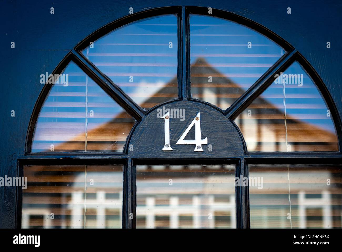 Haustür Nummer 14 mit einer Spiegelung eines anderen Hauses Stockfoto