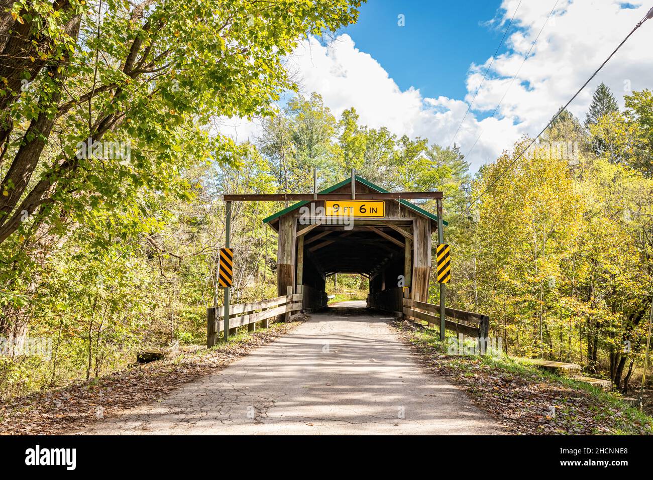 Die überdachte Brücke der Riverdale Road überquert den Grand River während der Herbstfärbung der Blätter im Ashtabula County, Ohio. Stockfoto