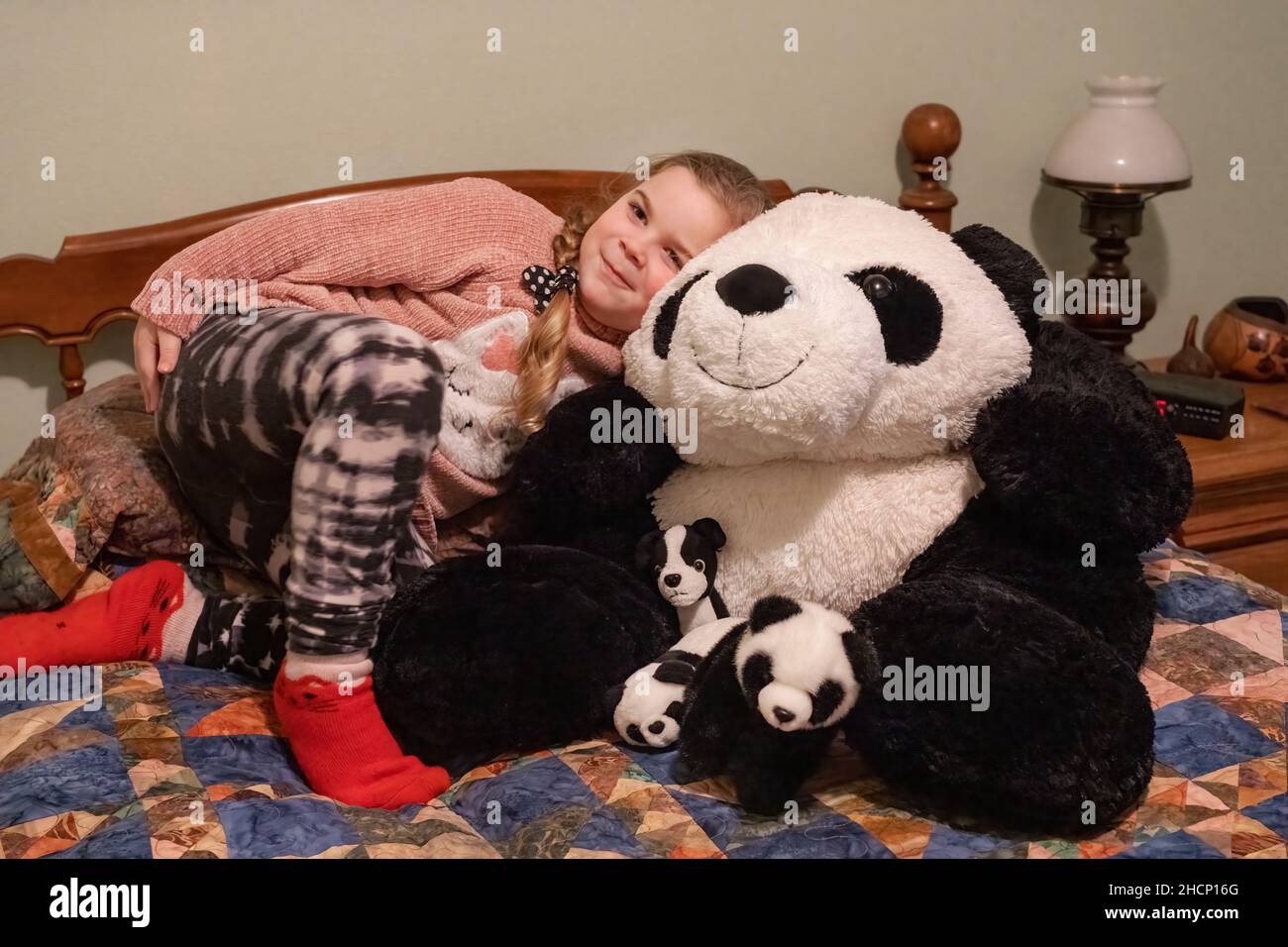 Issaquah, Washington, USA. 5-jähriges Mädchen, das einen großen und Baby gefüllten Pandabären auf einem Bett umarmt. (MR) Stockfoto