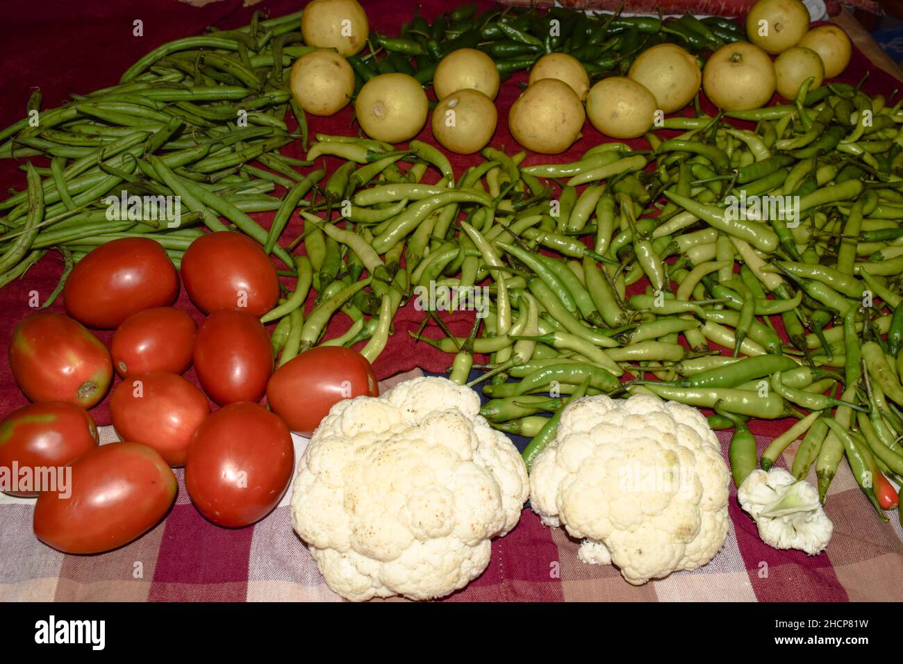 Frisches, hausgewachsenes Bio-Rohgemüse zu Hause. Viele Gemüse wie Tomaten, Zitronen, Blumenkohl, Bohnen und grüne Chilis gewaschen und getrocknet auf Tuch f Stockfoto