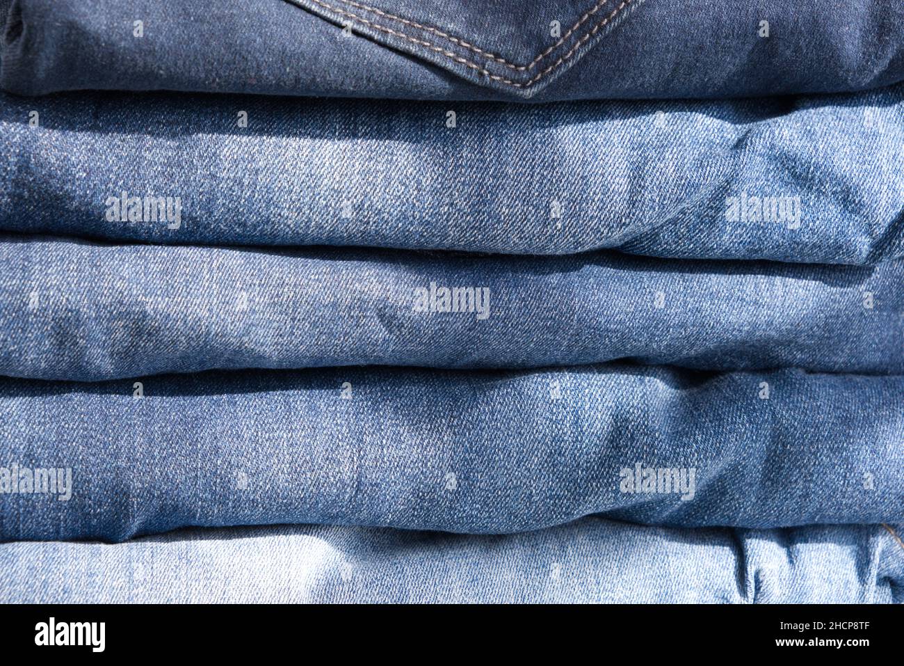 Haufen blauer Jeans auf hellem Hintergrund. Nahaufnahme Stockfoto