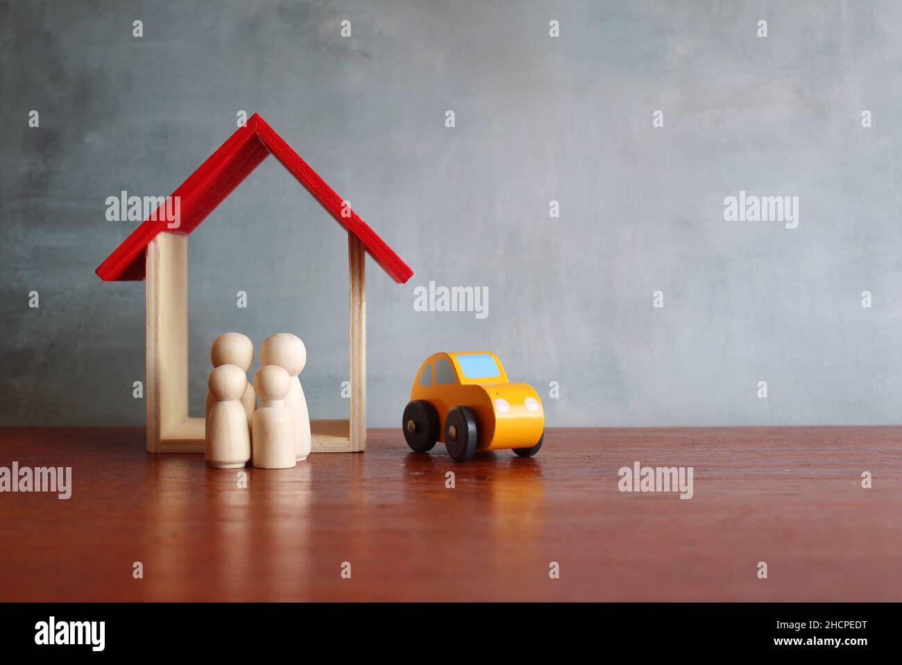 Familienplanung und Immobilienkonzept. Nahaufnahme des Holzspielzeughauses, Autos und Puppen. Stockfoto