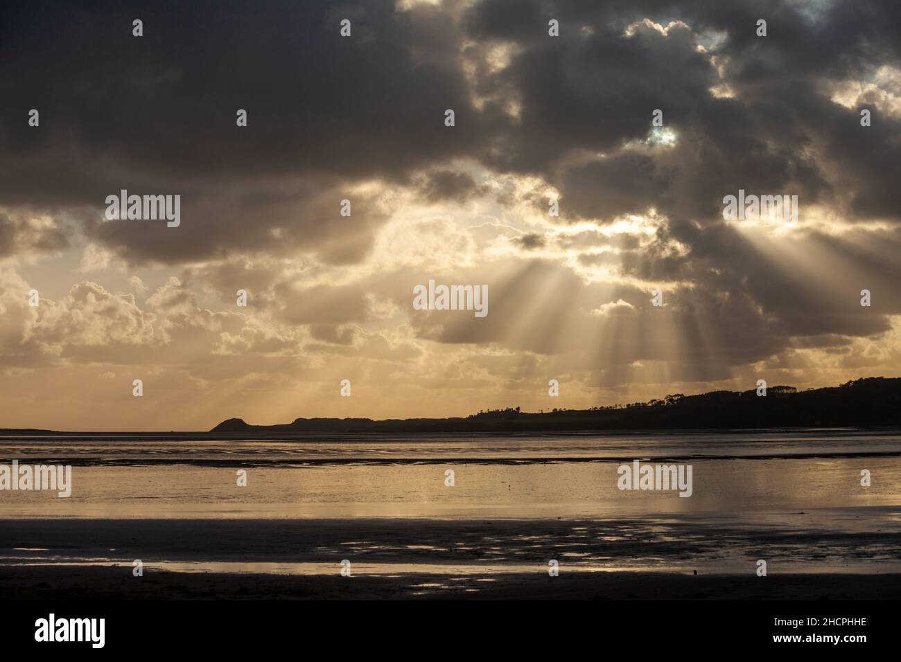 Wellen von Sonnenstrahlen brechen durch Wolken bei Malltraeth Anglesey, Wales Stockfoto