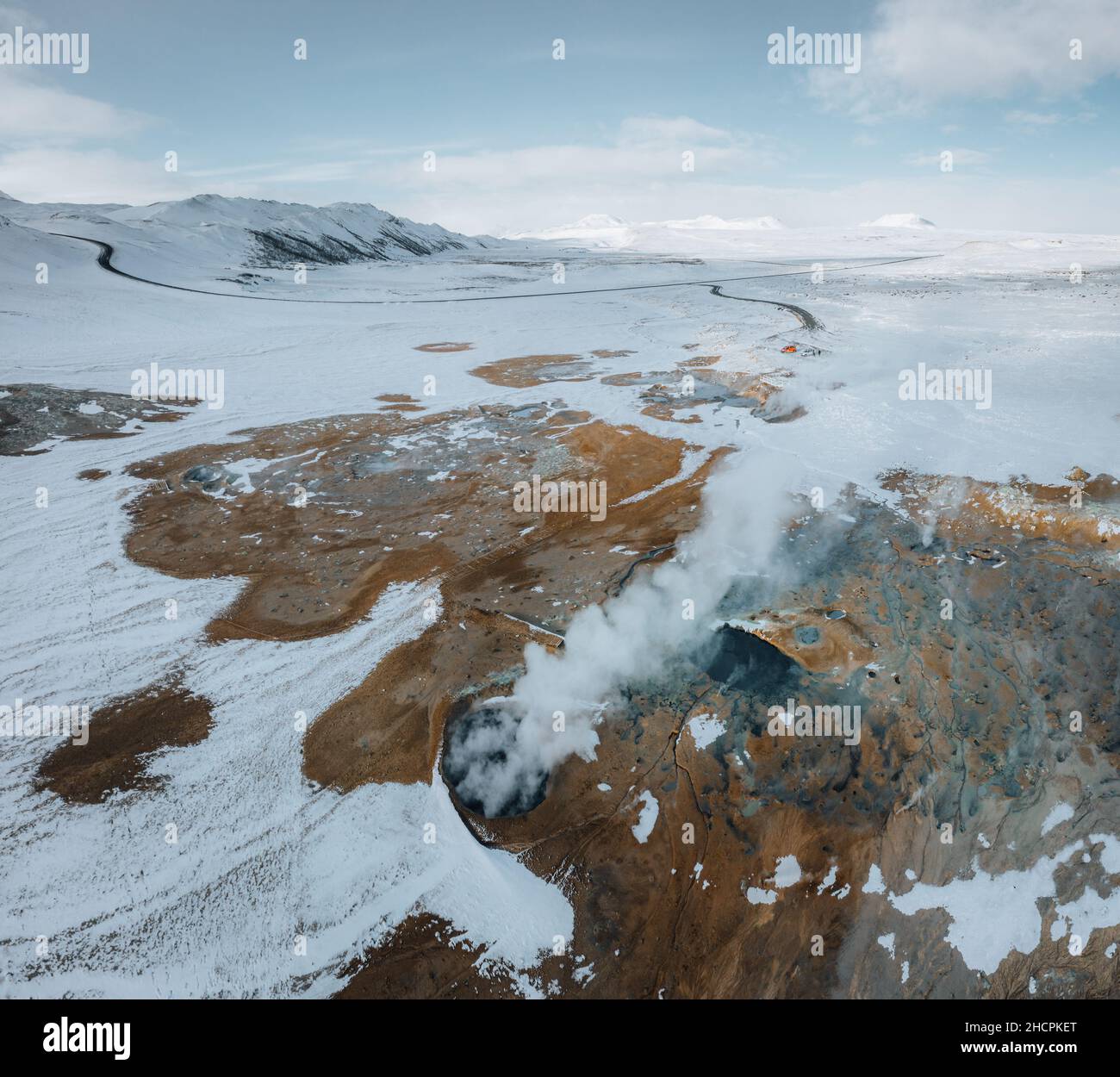 Luftdrohnenpanorama mit heißem Dampf aus dem Boden. Hverir ist ein geothermisches Gebiet in Myvatn. Landschaft bedeckt mit Schnee und orangefarbenem Boden. Stockfoto