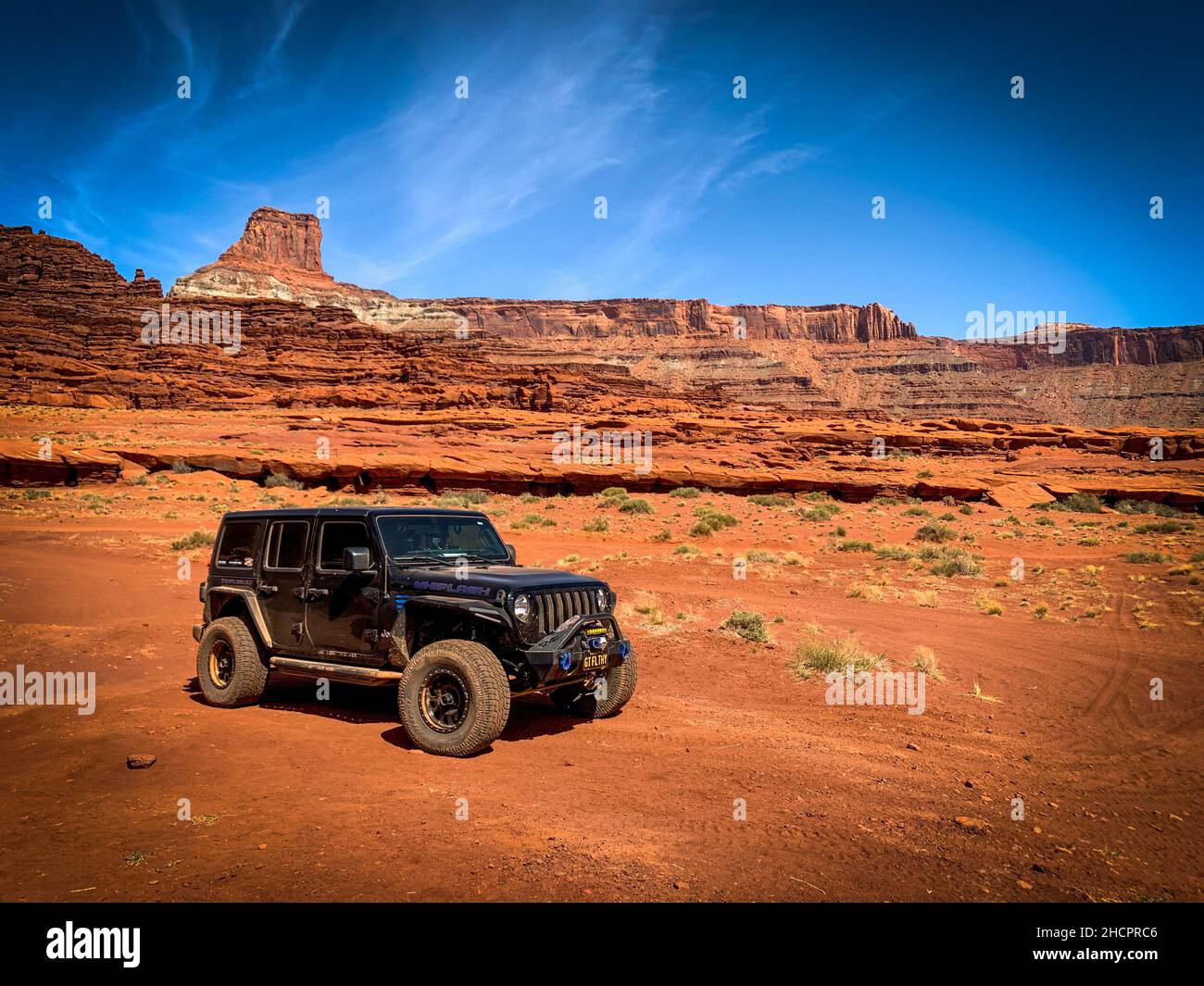 Epische Ansicht eines schnellen Jeep Wrangler in einer felsigen heißen Wüste in Moab, Utah, den Vereinigten Staaten Stockfoto