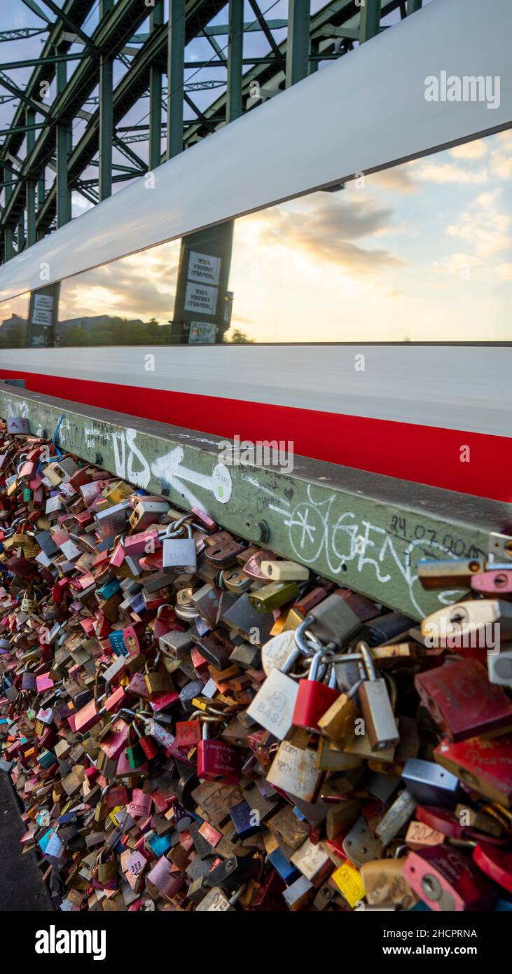 Zug fährt auf einer Brücke mit vielen bunten Schleusen in Köln, Deutschland Stockfoto