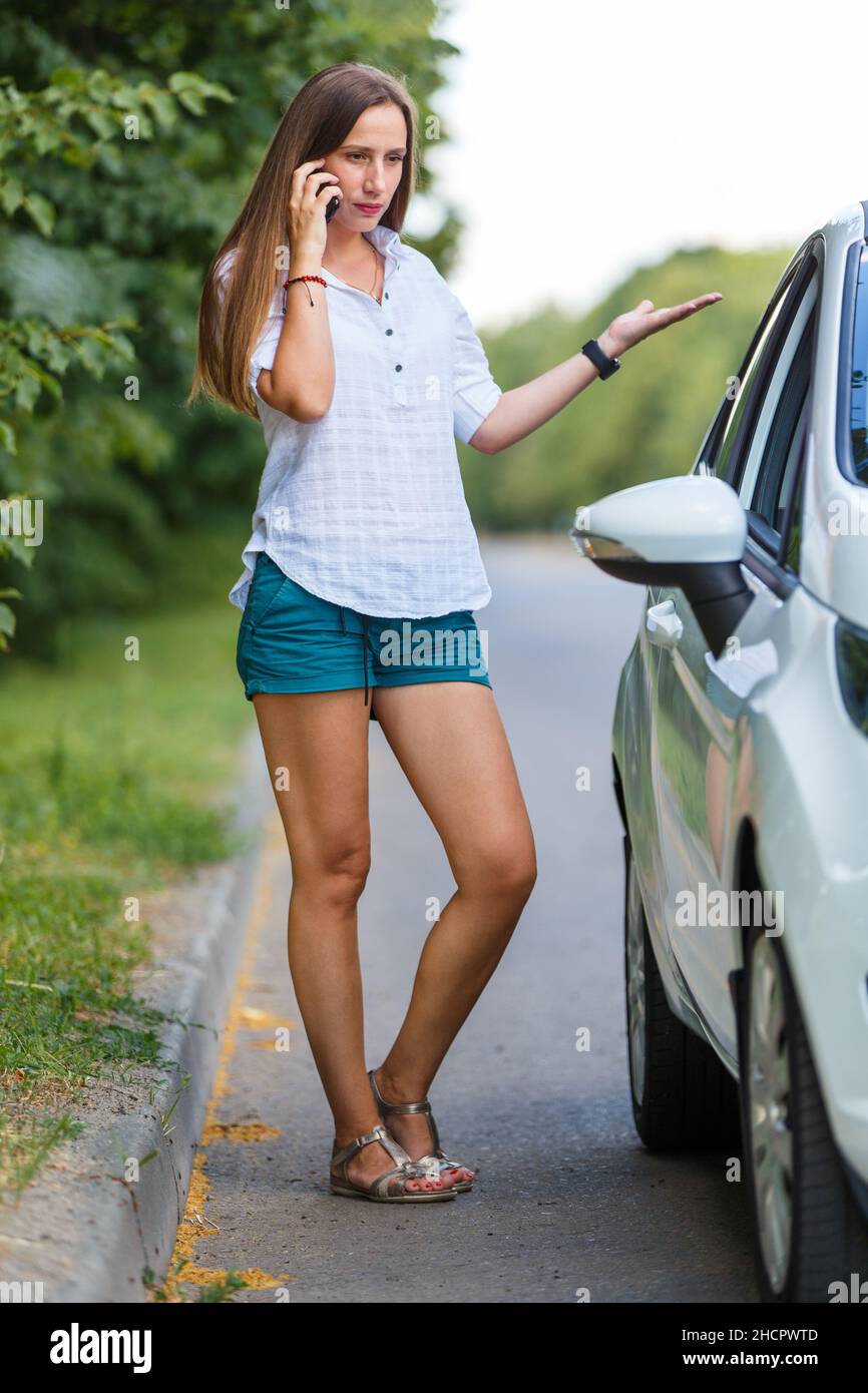 Junge Frau, die den Straßendienst wegen einer Fehlfunktion ihres Autos anruft Stockfoto