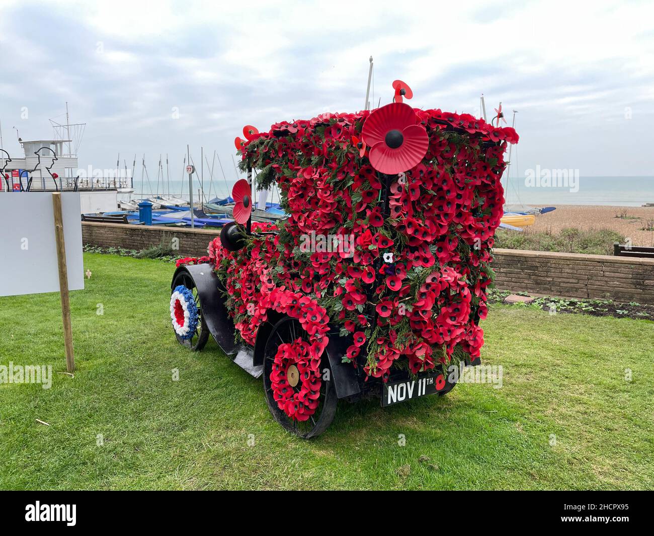 Ein klassisches Auto mit Mohnblumen bedeckt, um Gedenktag zu gedenken.Mohntag.Meereshintergrund.Bexhill Stockfoto