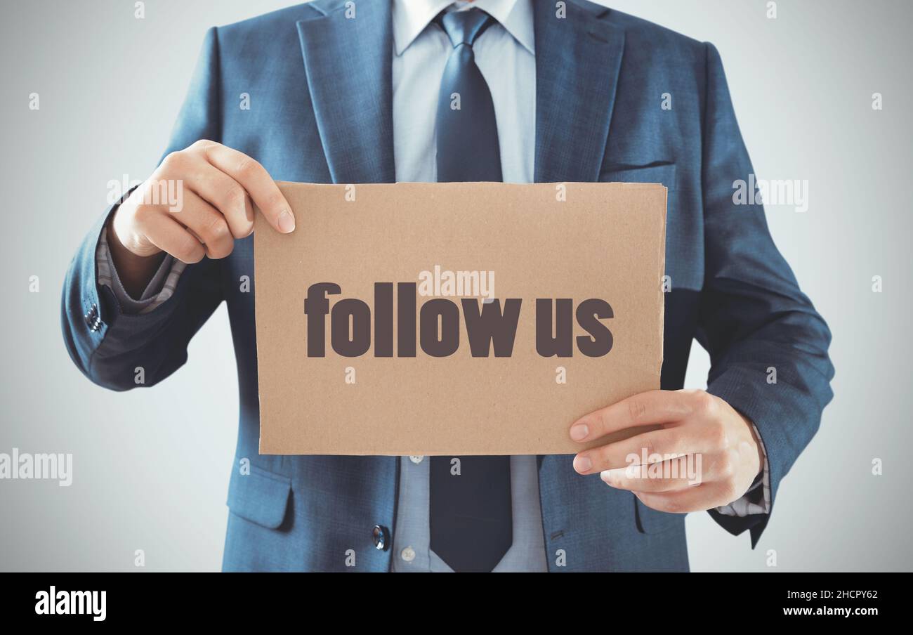 Geschäftsmann hält Pappteller mit Follow US Worten. Marketing, Social-Media-Konzept Stockfoto