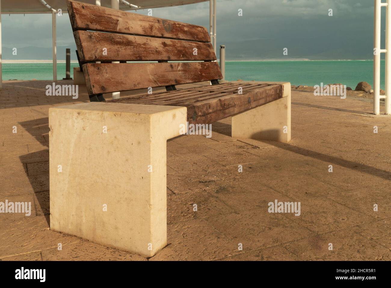 Eine Holzbank mit Marmorseiten steht unter einem Baldachin am Ufer des Toten Meeres Stockfoto